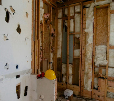 Chantier de rénovation avec isolation murale, ossature bois et travaux de plomberie apparents