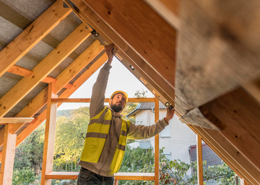 Artisan réalisant des travaux de charpente et d’aménagement sous toiture en bois rénovée