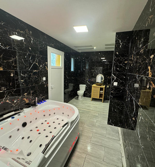 Salle de bain haut de gamme avec baignoire balnéo, carrelage effet marbre noir et douche moderne rénovée